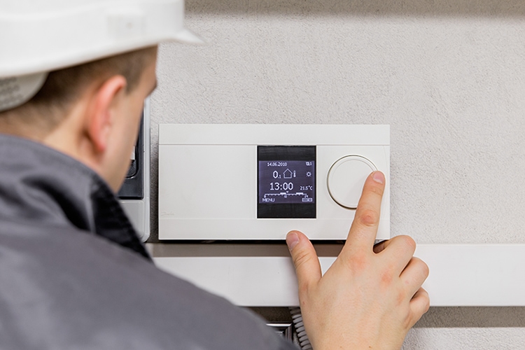 man in white hard hat adjusting thermostat