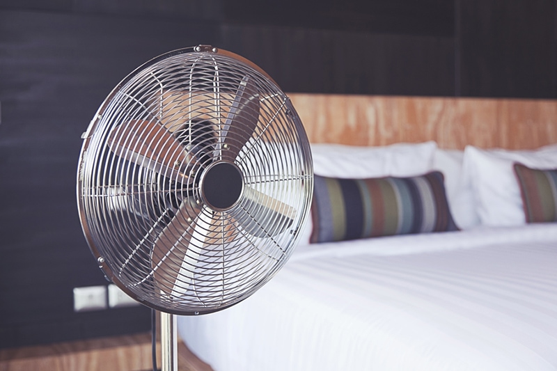 Old electric fan near the bed in the room