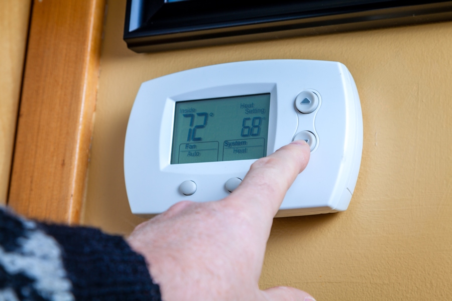 Homeowner Adjusting Temperature On Their Thermostat