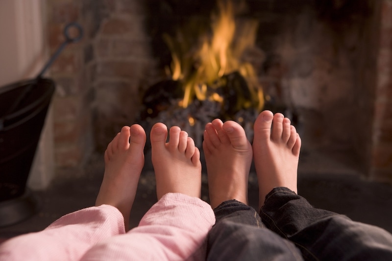 Children&#039;s feet warming at a fireplace sitting down in living room