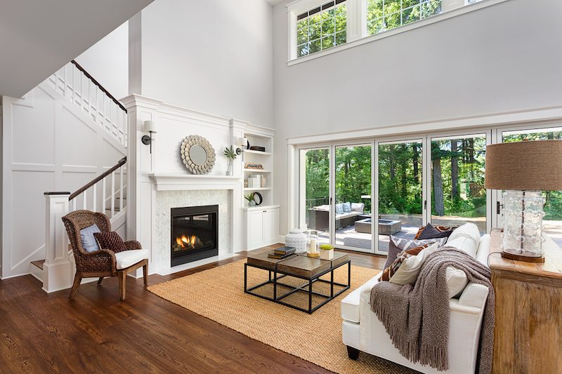 Beautiful living room interior with hardwood floors and fireplace in new luxury home with sliding glass doors and vaulted ceiling