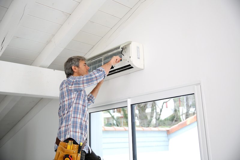 Man performing ductless maintenance on a ductless AC in Wausau